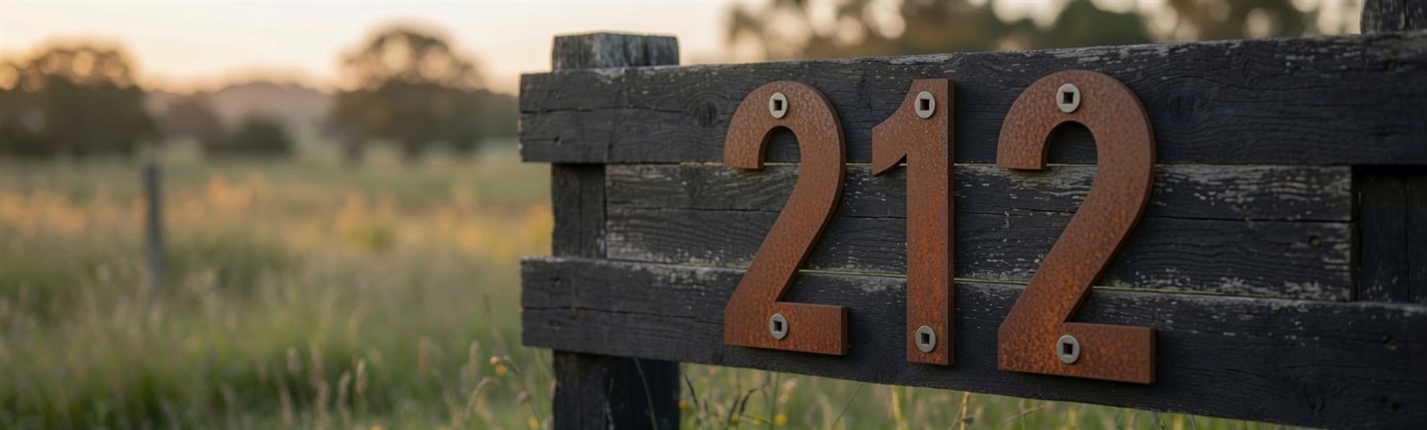 Corten house numbers on a fence at dusk